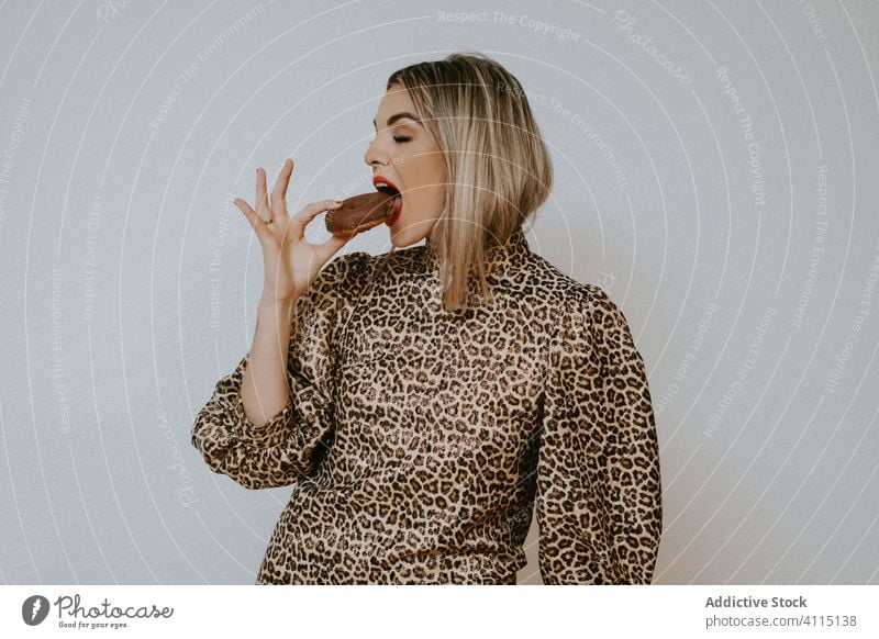 Fröhliche stilvolle Frau isst Donuts essen Lächeln Stil Model Biss schließt die Augen trendy Kleid Leopard drucken Doughnut Dessert Gebäck geschmackvoll