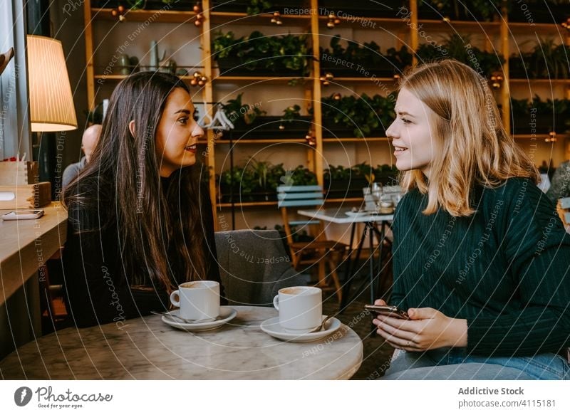 Freundinnen ruhen sich in gemütlichem Cafe aus Frauen Café Lachen Zusammensein Kaffee Smartphone benutzend Witz lässig Wochenende jung Sitzung Restaurant