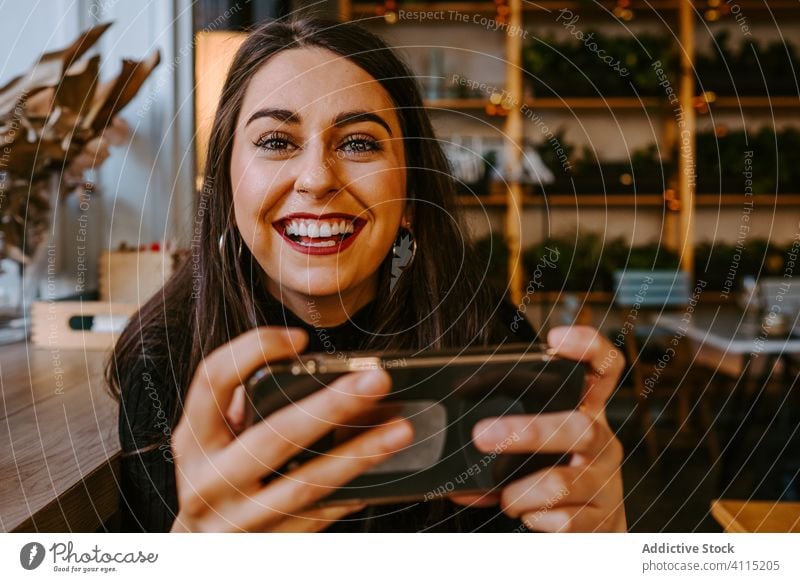Junge Frau benutzt Smartphone in einem Cafe benutzend Café Stil ruhen sitzen Fenster modern jung Outfit Browsen gemütlich Restaurant Pause Mobile Telefon trendy