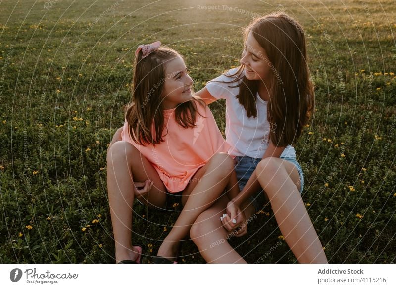 Glückliche Kinder, die sich auf der grünen Wiese umarmen Schwester Natur Zusammensein Umarmung sitzen Gras Sommer Mädchen Landschaft heiter Teenager