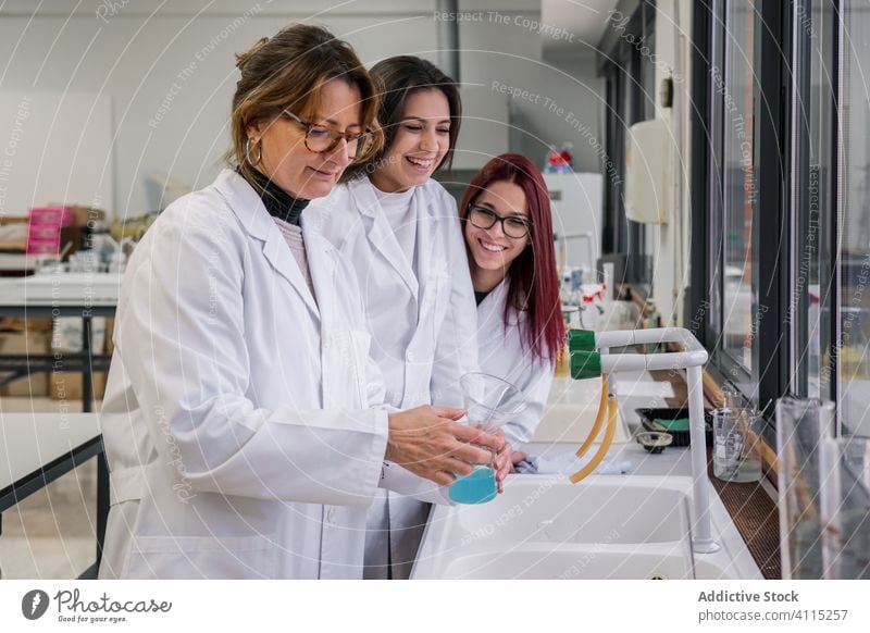 Studentinnen beobachten einen Mentor bei einem Experiment im Labor Schüler Wissenschaftler Frauen zuschauen Lehrer forschen Chemie Flasche liquide Prüfung