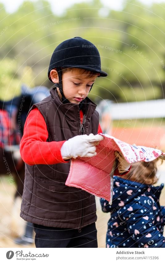 Kleiner Jockey mit Schabracke Junge Reiterin Schule Lektion Unterlage Sattel führen vorbereiten Hobby Kind Schutzhelm Sicherheit Pferderücken weich Decke Sport