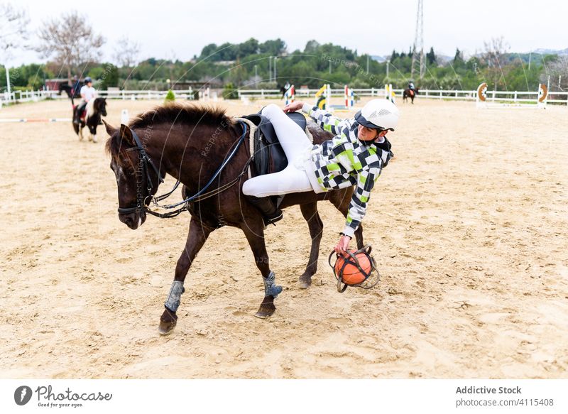 Teenager spielen Spiel mit rosa Ball vom Pferd fallen Training Arena Pferderücken Sand Lektion Schule Jockey Junge Boden braun Reiterin Sattel Tier