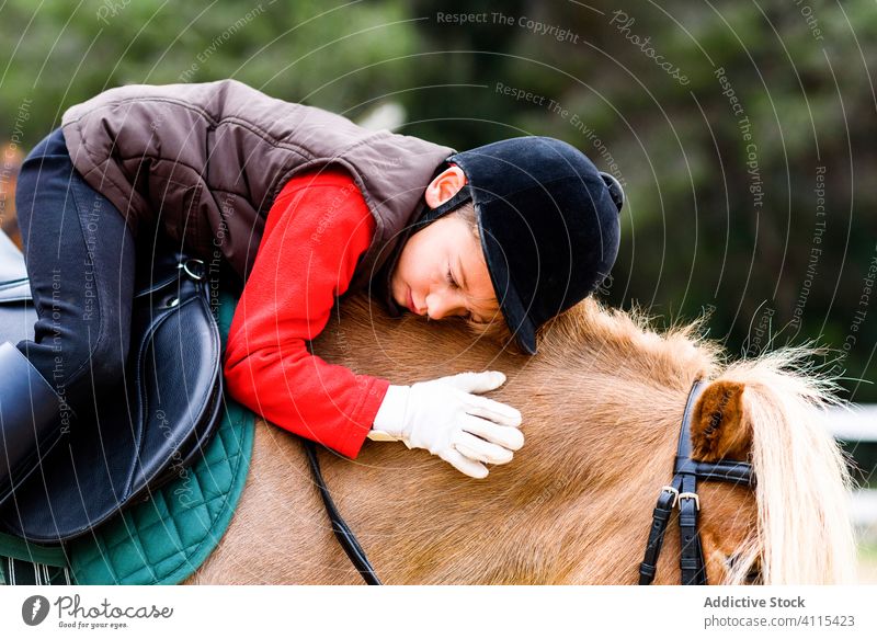 Kind umarmt Pony auf der Koppel Ponys Umarmung Sattelkammer Reiterin Jockey Schule Lektion Liebe Freund sitzen Mähne Pferderücken Tier Schutzhelm Umarmen