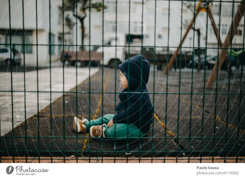 Kind weint auf dem Spielplatz Kindheit 1-3 Jahre weinen Kaukasier Seitenansicht durch Zaun Gefühle Außenaufnahme Lifestyle Kleinkind Farbfoto Mensch authentisch
