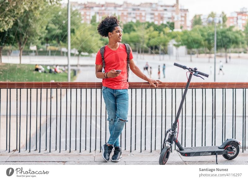 Afroamerikanischer Junge auf der Straße Afro-Look jung Mann schwarz Afroamerikaner Lächeln urban Vorderansicht Elektroroller außerhalb Gerät Glück