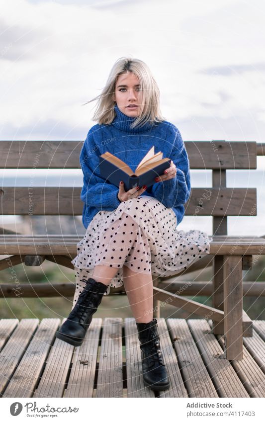 Junge Frau liest Buch an der Meeresküste Terrasse MEER Bank Strand ruhen lesen jung blau Pullover Natur sich[Akk] entspannen hölzern Stil Urlaub genießen