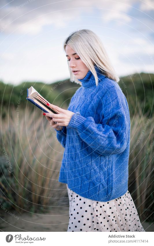 Junge Frau steht und liest ein Buch blau Pullover lesen jung lässig ernst Natur blond selbstbewusst modern Bildung Hobby Schüler ruhen klug lernen Wissen Stil