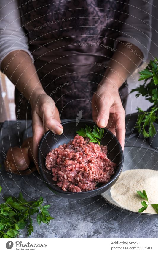 Crop-Frau zeigt Hackfleisch zerkleinern Fleisch zeigen Petersilie Koch Tisch Lebensmittel Mahlzeit frisch vorbereiten Küche rustikal Bestandteil Feinschmecker