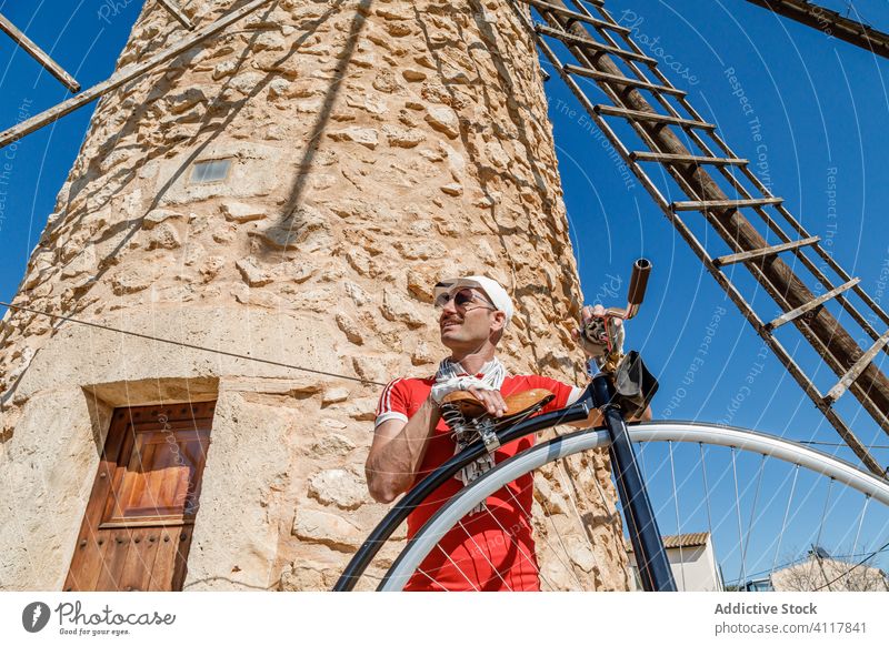 Erwachsener Sportler mit Hochrad auf der Straße gegen eine alte Windmühle Mann Fahrrad Rad Pfennigfuchser Radfahrer Sightseeing reisen Ausflugsziel Architektur