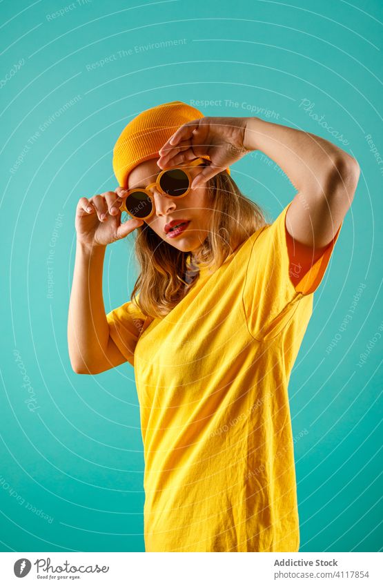 Trendige junge Dame beim Einstellen der Sonnenbrille Frau Stil modern ausrichten farbenfroh hell selbstbewusst urban lässig Model trendy cool pulsierend lebhaft