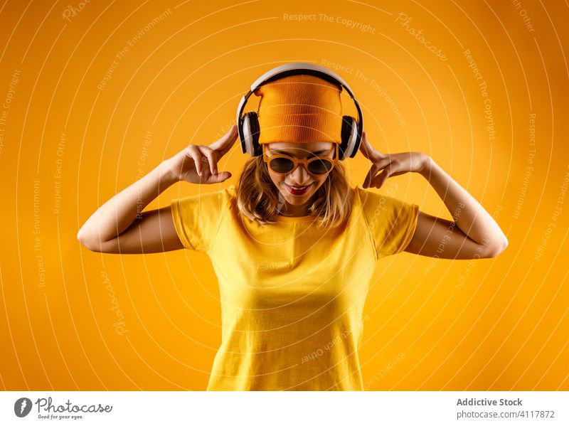 Positive Frau beim Musikhören modern zuhören positiv Sonnenbrille Stil Kopfhörer hell trendy Mode heiter Accessoire Glück Hipster pulsierend Lächeln lebhaft