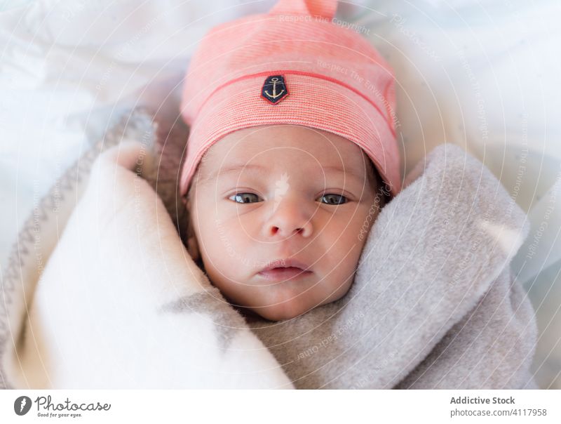 Niedliches Baby in Decke und Hut auf dem Bett liegend neugeboren bezaubernd Kind Lügen umhüllen Porträt winzig rosa süß wenig Säugling Kindheit Kinderbetreuung
