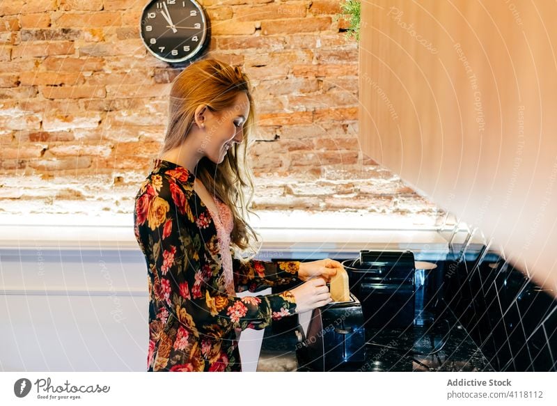 Junge Frau bereitet morgens Toasts vor Frühstück Zuprosten vorbereiten Küche Toaster Morgen heimwärts gemütlich jung Lifestyle sich[Akk] entspannen Stil trendy