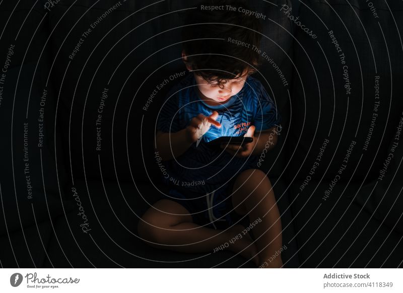 Neugieriger kleiner Junge stöbert zu Hause auf einem Smartphone Kind wenig Bildung Browsen Anwendung Hausaufgabe Apparatur Mitteilung Anschluss