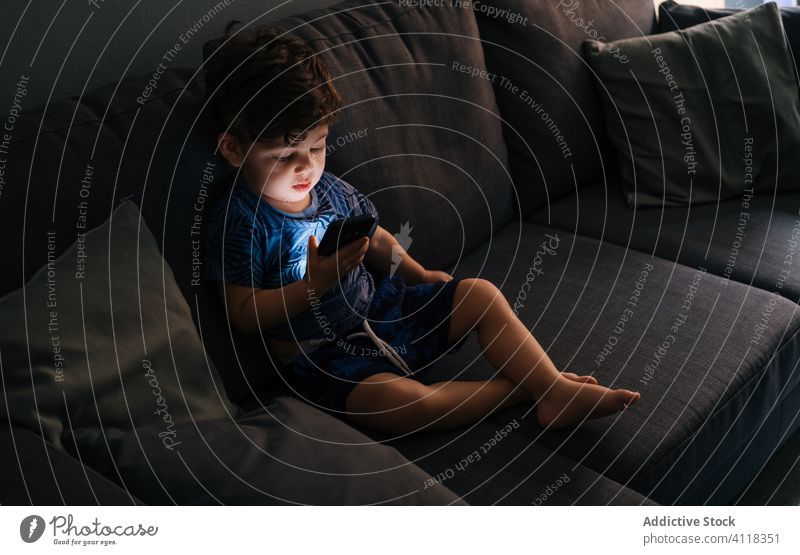 Neugieriger kleiner Junge stöbert zu Hause auf einem Smartphone Kind wenig Bildung Browsen Anwendung Hausaufgabe Apparatur Mitteilung Anschluss