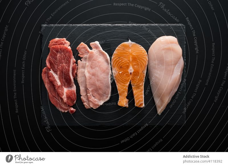 Flachlegen von verschiedenen Arten von eiweißreichem Fleisch auf einem Schneidebrett Produkt Protein Filet Rindfleisch Fisch Hähnchen Schweinefleisch
