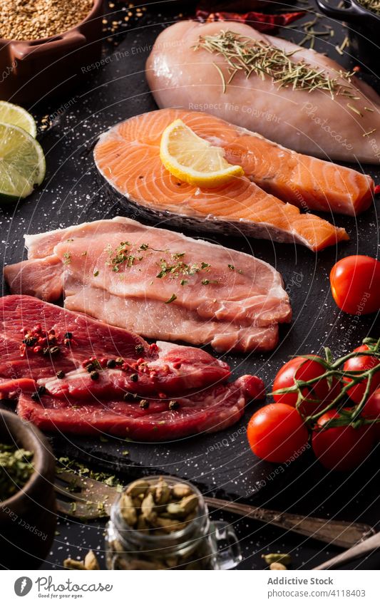 Flache Lage von Proteinen, umgeben von Gewürzen und Würzmitteln auf dem Tisch Produkt Fleisch Lachs Fisch Filet Lebensmittel Paprika Schneidebrett Löffel