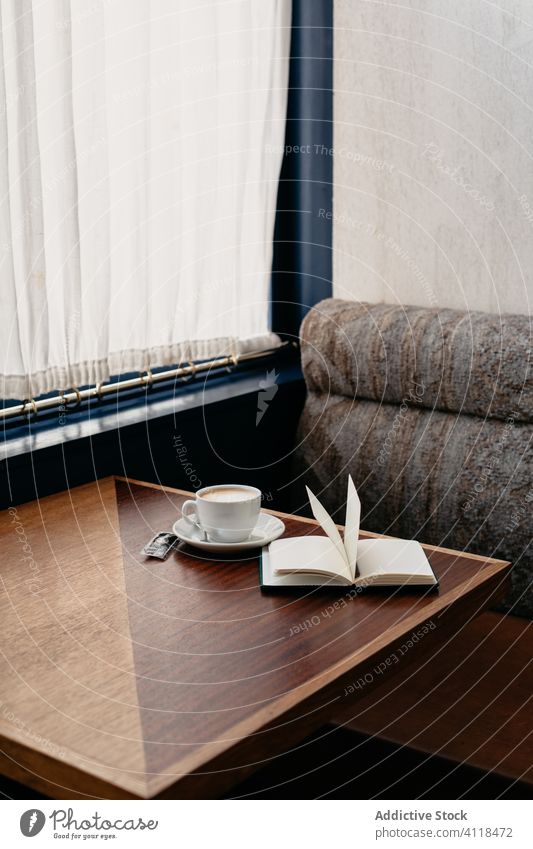 Nahaufnahme einer Tasse Kaffee und eines Buches auf einem Tisch Notebook Café Bar trinken Restaurant Tee hölzern Geschäftsfrau Innenbereich Sofa allein