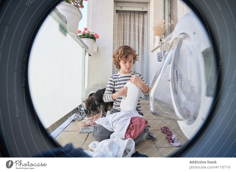 Kind mit Hund hat Spaß in der Waschküche Waschen Maschine Wäscherei Spaß haben unordentlich spielerisch Stoff heimwärts Haustier Zusammensein Lächeln Junge