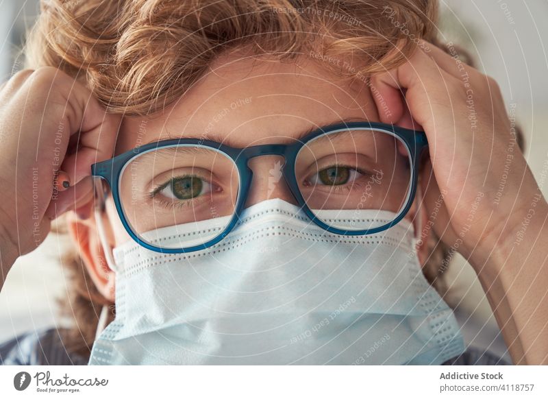 Junge mit medizinischer Maske und Brille Mundschutz Quarantäne klug heimwärts Coronavirus Pandemie verhindern Kind Krankheit behüten Gesundheitswesen Sicherheit