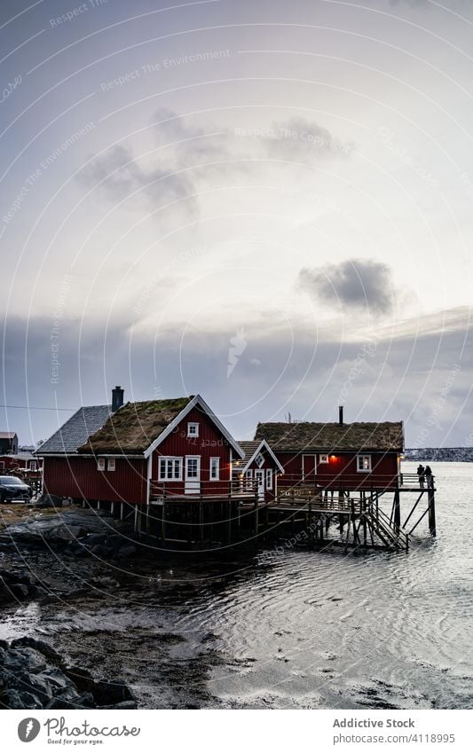 Kleine Häuschen am Flussufer unter bewölktem Himmel Haus Strand Wasser Hafengebiet Ufer Fjord malerisch idyllisch Cottage ruhig Landschaft Norwegen Küste