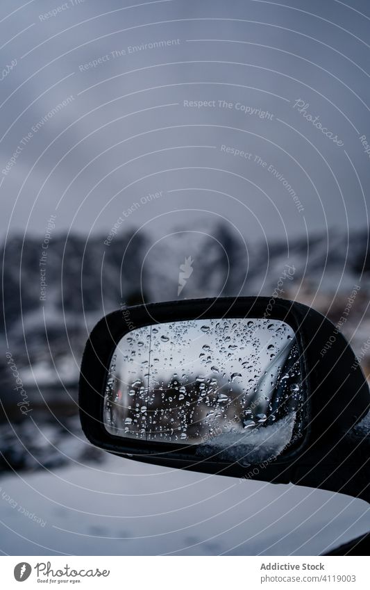 Mit Wassertropfen bedeckter Autospiegel vor verschneitem Gelände bei bedecktem Himmel Spiegel PKW Winter Reflexion & Spiegelung Regen Tropfen Autoreise Ausflug