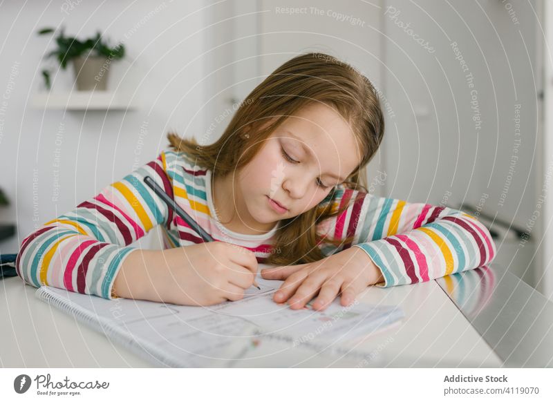 Mädchen macht Hausaufgaben am Tisch heimwärts schreiben Notebook klug lernen Fokus sitzen Kind Schule Schüler Notizblock Hinweis Bleistift Bildung ernst Pupille