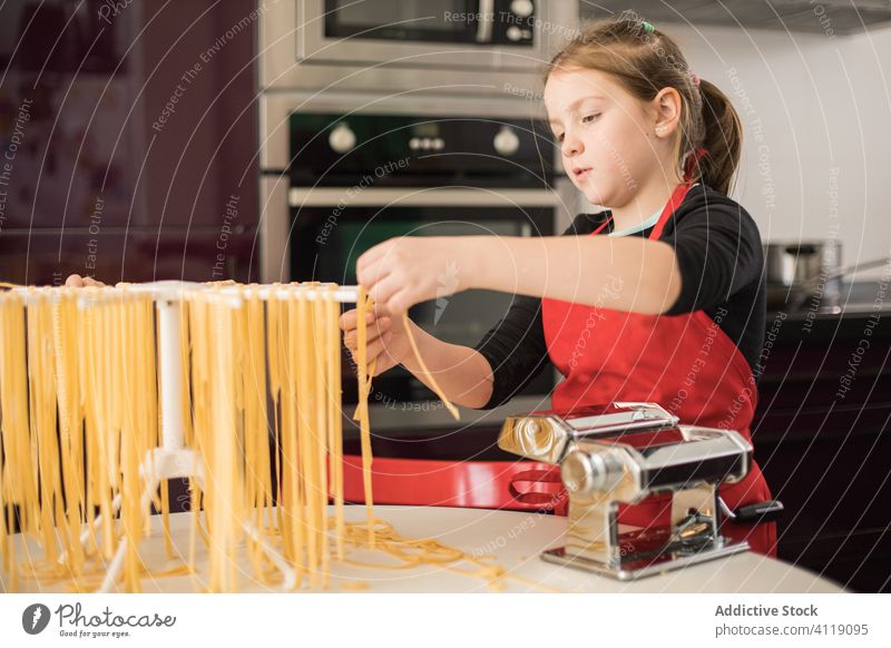 Kleines Mädchen macht in der Küche Nudeln Kind Spätzle machen trocknen hängen Maschine vorbereiten Lebensmittel lernen Schürze Frau ernst Koch Ablage