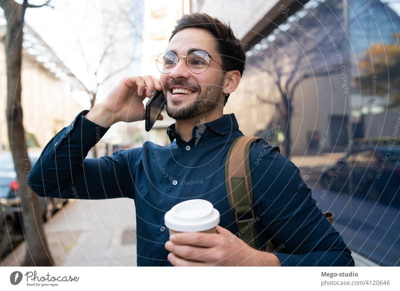 Junger Mann beim Telefonieren im Freien. jung Mobile urban Kaffee wegnehmen Anschluss Apparatur Porträt trinken Drahtlos Beteiligung laufen Blick Tippen