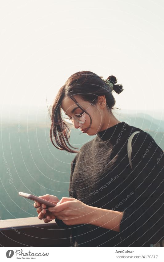 Junge Frau überprüft sein Telefon in einem Berg an einem sonnigen Tag Menschen Mitteilung Porträt Technik & Technologie Model professionell Lächeln Business