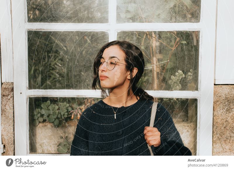 Eine junge marokkanische Frau vor einem weißen Holzkristallfenster, das mit Pflanzen gefüllt ist, mit Kopierraum Person Dame Model außerhalb Lächeln hübsch
