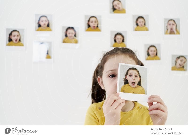 Kleines Mädchen mit eigenen Sofortbildern Kind Foto Bild verschiedene Wand Deckfläche expressiv sofort lässig wenig Kulisse kreativ Fotografie niedlich Porträt