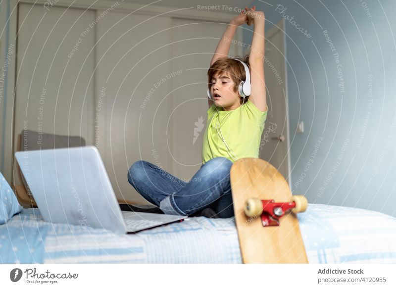 Müdes Kind surft zu Hause auf dem Laptop heimwärts traurig benutzend gelangweilt drücken Quarantäne Bett Junge Browsen Internet Gerät lässig online Apparatur