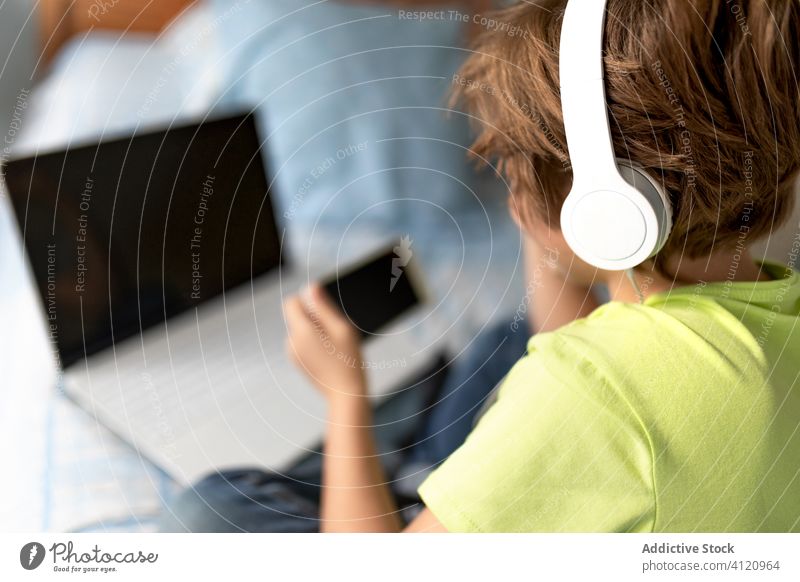 Junge schaut Spiel auf Laptop Kind Schlafzimmer heimwärts Bett Kopfhörer Apparatur Gerät Freizeit lässig Lifestyle Technik & Technologie heiter unterhalten