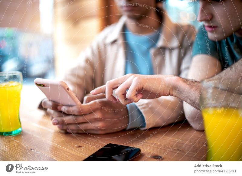 Anonymes schwules Paar benutzt Smartphone im Café Termin & Datum benutzend Männer jung soziale Netzwerke Tisch sitzen Zusammensein romantisch Gerät Apparatur