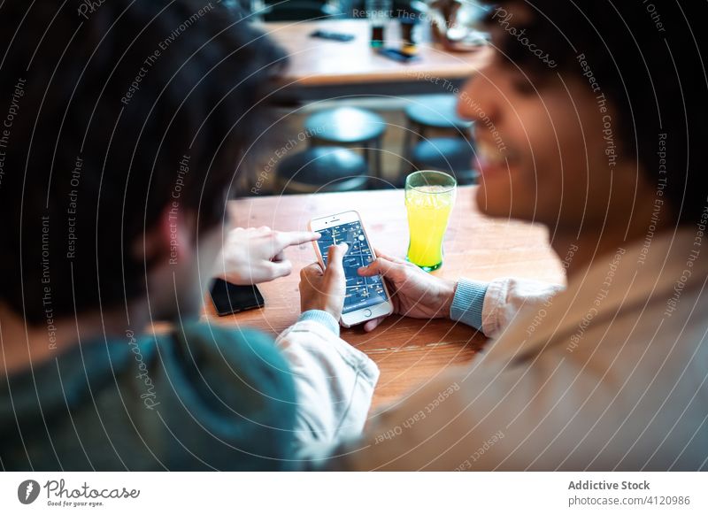 Anonymes schwules Paar benutzt Smartphone im Café Termin & Datum benutzend Männer jung soziale Netzwerke Tisch sitzen Zusammensein romantisch Gerät Apparatur