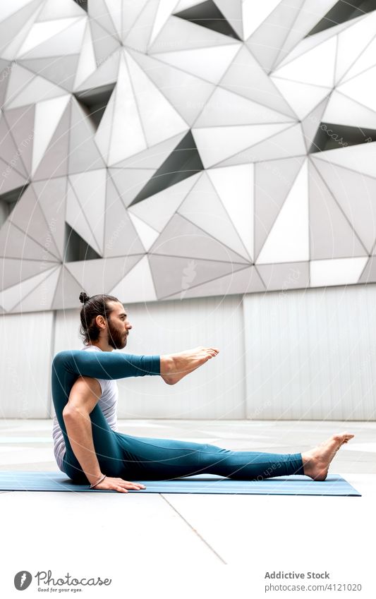 Flexibler Mann bei Yoga-Übung Training Geometrie Asana beweglich modern Dehnung Fitness Form männlich Sportbekleidung Architektur Zeitgenosse Wand geräumig Zen