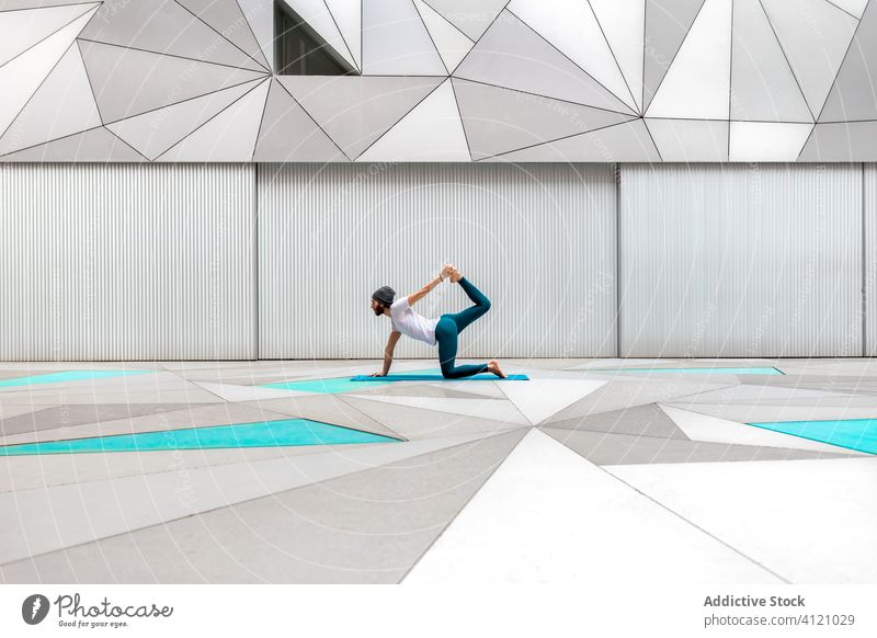 Mann macht Yoga in geräumigem Raum Übung Training Geometrie modern Dehnung Fitness Form männlich Sportbekleidung Architektur Zeitgenosse Wand Zen Gleichgewicht