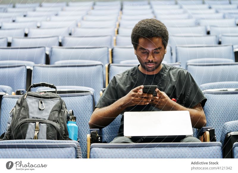 Ethnische Studenten nutzen Smartphones während der Vorlesung Schüler benutzend dozieren lernen ethnisch Sitz sitzen Aula modern Mann schwarz Afroamerikaner