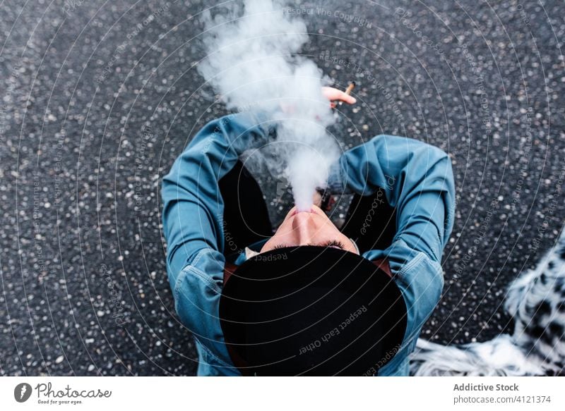 Unbekannte Frau mit Hut raucht Zigarette auf dem Boden Rauch Straße ruhen Tabak Hund Süchtige Habitus Spaziergang Asphalt schwarz Stil Subkultur Hipster modern