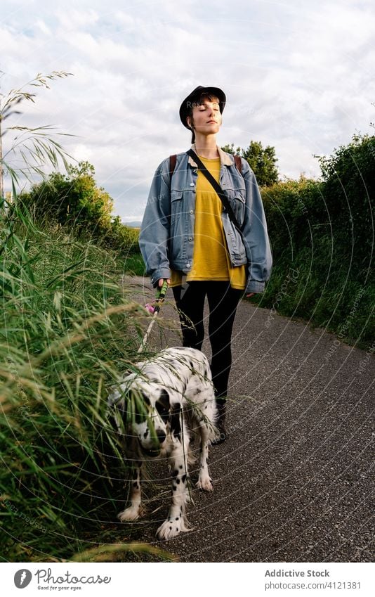 Frau spaziert mit Hund auf einer Straße im Grünen Spaziergang Landschaft Park Natur Windstille Frischluft genießen Frieden Begleiter schlendern Zusammensein