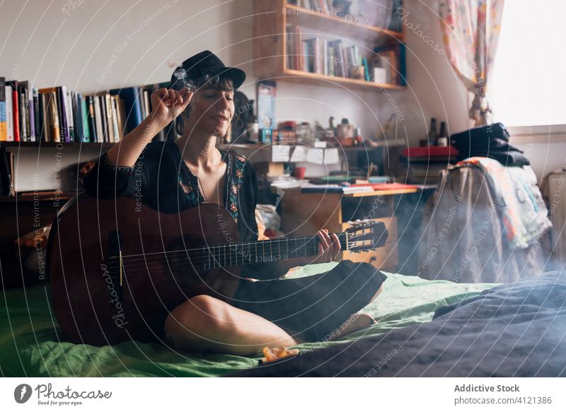 Weiblicher Hipster mit Akustikgitarre, der zu Hause kifft Rauch Unkraut Frau Gitarre akustisch sich[Akk] entspannen Marihuana Gitarrenspieler heimwärts Musik