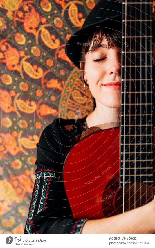 Zufriedene Frau umarmt Gitarre mit geschlossenen Augen akustisch Hipster Umarmung ruhen heimwärts Inhalt Wochenende Gitarrenspieler Freude Gelassenheit trendy