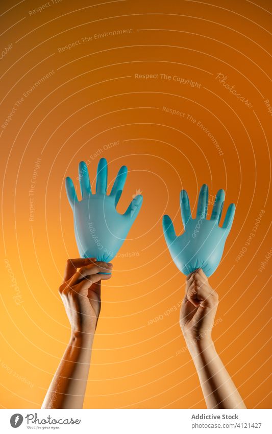 Crop Person mit Handschuh Luftballons im Studio Wellenhand gestikulieren medizinisch zeigen chirurgisch Zeichen Coronavirus behüten Konzept kreativ Spaß