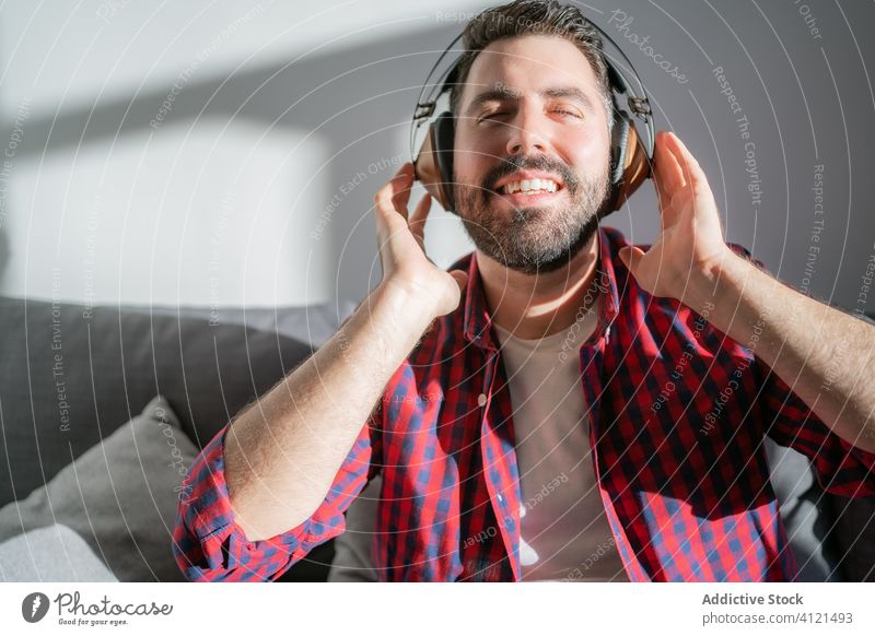 Junger Mann hört zu Hause Musik heimwärts jung Freizeit lässig Kopfhörer Technik & Technologie Kaukasier Erwachsener Lifestyle Glück Sofa Person Erholung modern