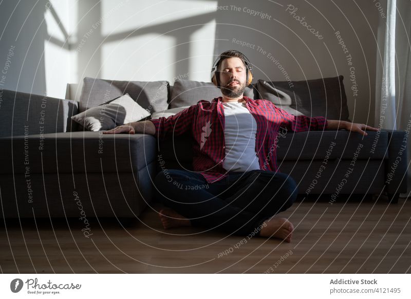 Junger Mann hört zu Hause Musik heimwärts jung Freizeit lässig Kopfhörer Technik & Technologie Kaukasier Erwachsener Lifestyle Glück Sofa Person Erholung modern