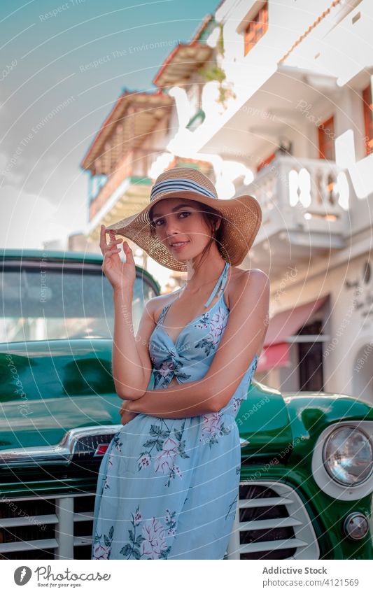 Fröhliche junge Frau mit Hut steht in der Nähe von Retro-Auto auf der Straße Sommer Mode Stil retro PKW Gebäude Porträt Lächeln Urlaub genießen Fahrzeug