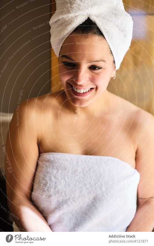 Fröhliche Frau sitzt im Handtuch in der Nähe der Tür nach einem Bad Körperpflege Dusche nass Lachen Wellness heiter froh zufrieden Glück genießen freundlich