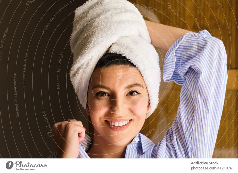 Glückliche Frau mit Handtuch auf dem Kopf nach einem Bad zu Hause Zahnfarbenes Lächeln Dusche frisch Sauberkeit Morgen Hygiene sich auf die Hand lehnen